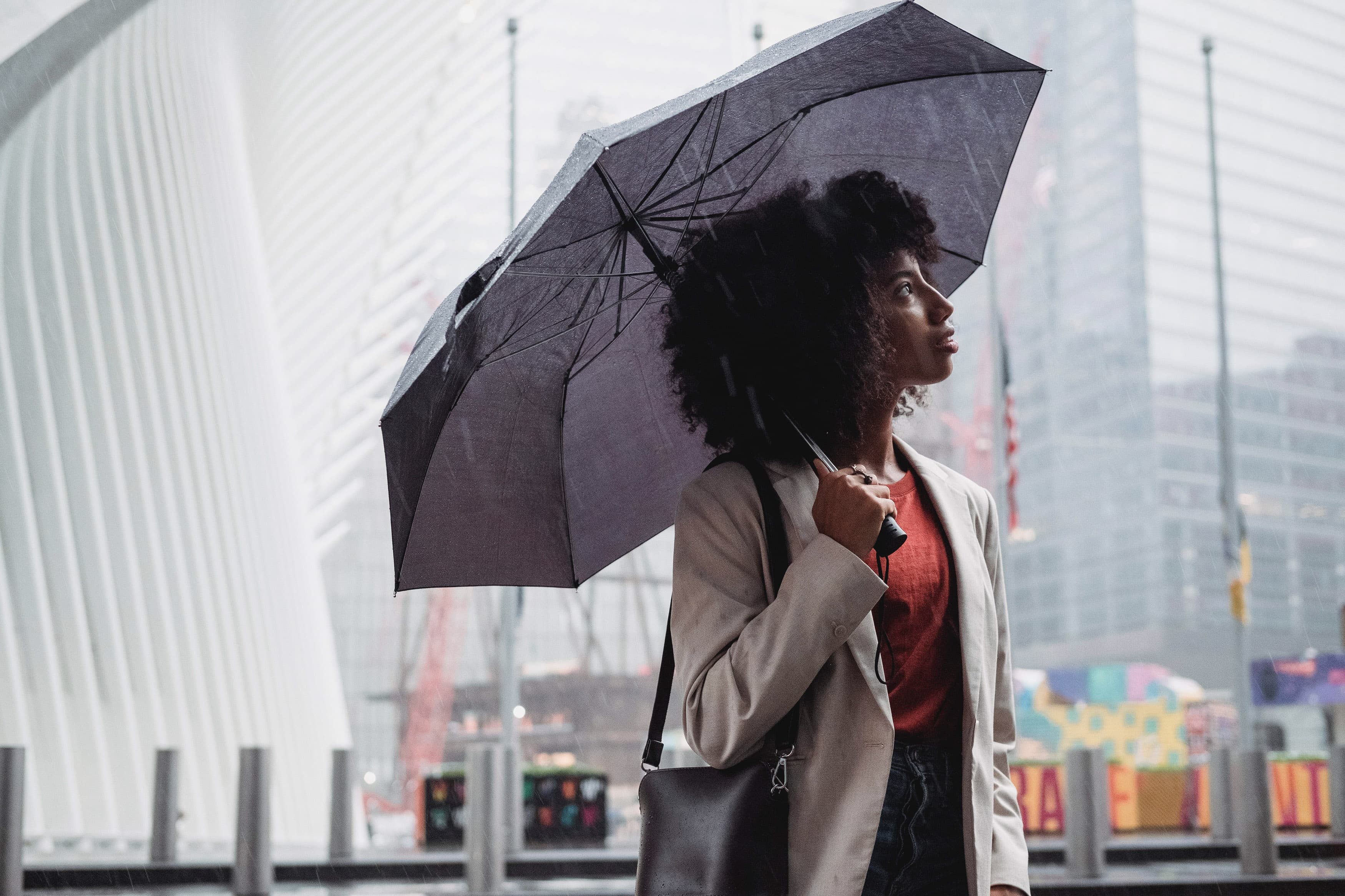 woman with umbrella in rain looking at sky